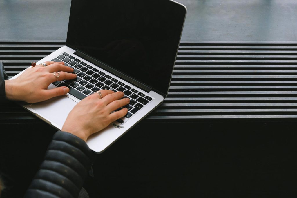 Close-up of hands typing on a sleek laptop, ideal for freelance work.